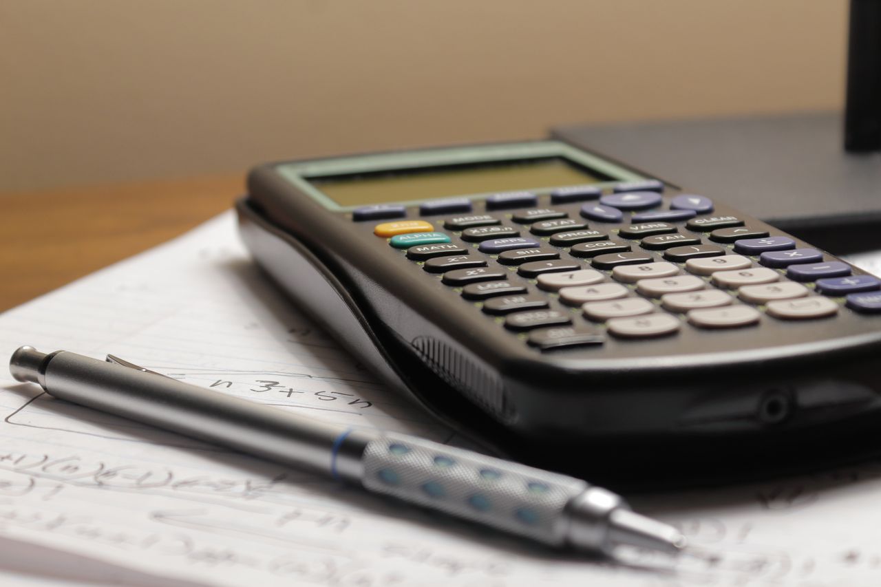 Services A detailed view of a calculator and pen resting on mathematical notes, ideal for educational and financial themes.